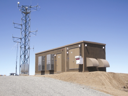Telecommunications shelter with wall-mount air conditioning in a remote desert location
